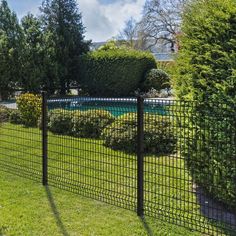 a black iron fence in the middle of a green yard next to a swimming pool