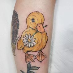 a yellow duck with a daisy in its beak and wings on the leg is shown