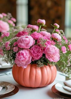 a vase filled with pink flowers sitting on top of a white table covered in plates