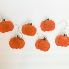 five orange pumpkins hanging from string on white background