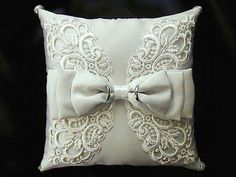 a white pillow with an embroidered bow on it's front and back, sitting on a black background