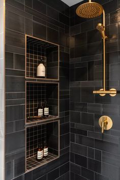 a shower head and shelves in a bathroom with black tiles on the wall behind it