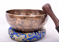 a large metal singing bowl sitting on top of a blue and gold object