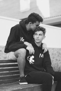 two young men sitting on a park bench hugging each other's foreheads, black and white photograph