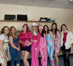 a group of women dressed in costumes posing for a photo with one woman wearing a pink hat