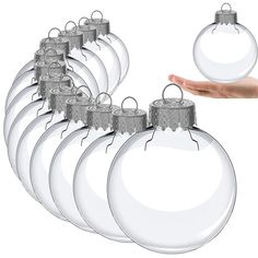 a hand holding a christmas ornament in front of a set of twelve glass baubles