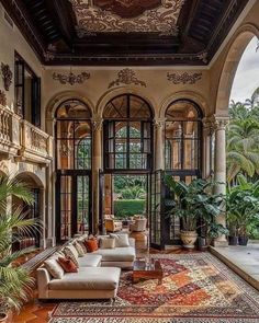 an ornate living room with large windows and lots of plants on the floor in front of it