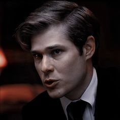 a man in a suit and tie is looking at the camera with an intense look on his face