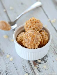 three peanut butter no bake bites in a small white bowl with a spoon next to it