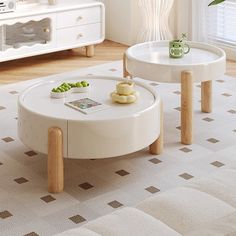 two white coffee tables sitting on top of a rug in a living room next to a window