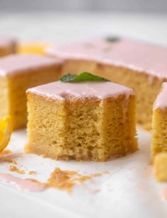 there is a piece of cake with pink icing on it and a lemon slice next to it