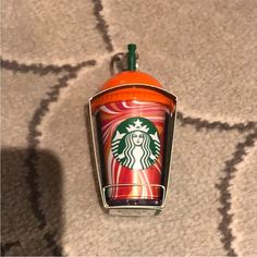 an orange starbucks cup shaped keychain hanging from a hook on a carpeted area