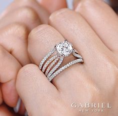 a woman's hand holding an engagement ring with two bands on top of it