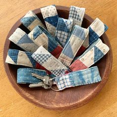 a wooden bowl filled with patchwork fabric and key fobs on top of a table