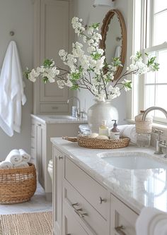 a white bathroom with flowers in a vase on the counter