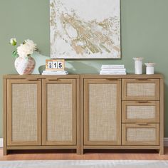 a sideboard with drawers and baskets on top in front of a green painted wall