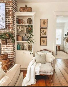 a living room filled with furniture and bookshelves next to a brick wall covered in pictures