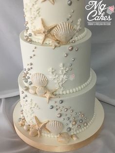 a three tiered cake decorated with seashells and pearls