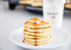 a stack of pancakes sitting on top of a white plate next to a glass of milk