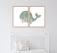 two paintings of a whale are hanging on the wall next to a crib