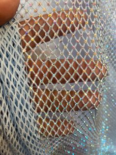 a person is holding onto a piece of sequins in front of a net