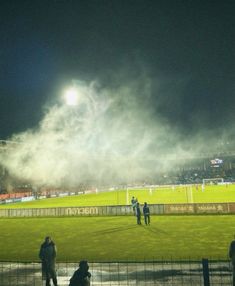 fireworks are lit up in the night sky at a soccer game as spectators look on