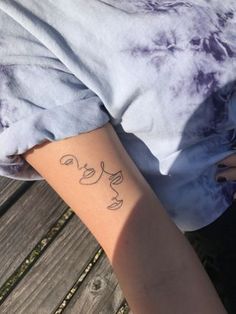 a woman's arm with a tattoo on it that has faces drawn on it