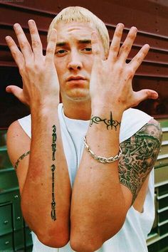 a man with tattoos on his arms and hands is holding up two fingers to the camera