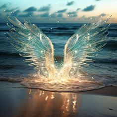 an angel wings floating in the water on top of a sandy beach at night time