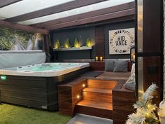 a hot tub sitting inside of a bathroom next to a wooden floor and green grass