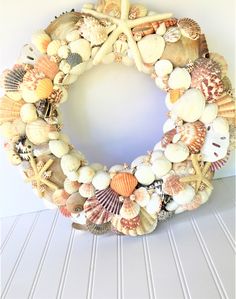 a wreath made out of seashells and starfish sits on a shelf next to a wall