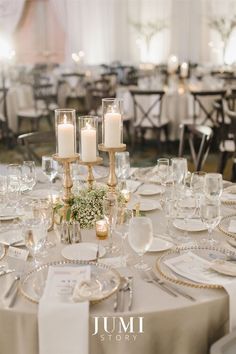 the table is set with white and gold plates, silver napkins, and candles