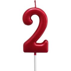 a red birthday candle with the number two on it's top, in front of a white background