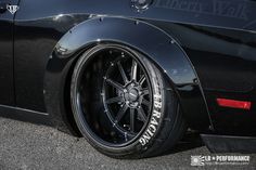 the front end of a black sports car with chrome rims on it's tires