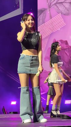 two girls on stage with one holding a cell phone to her ear and the other standing up