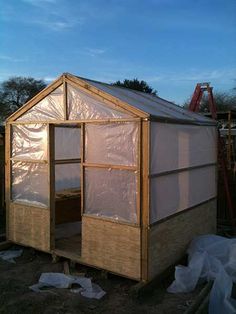 a small house with plastic covering on the roof and walls, in front of a blue sky