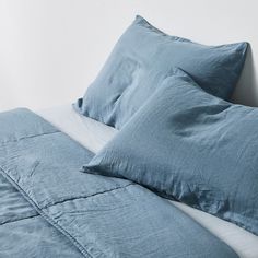 a bed with blue sheets and pillows on it