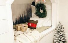 a white bed sitting under a window next to a christmas tree