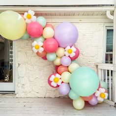 balloons are arranged in the shape of a letter k on a porch with flowers and daisies