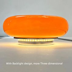 an orange table lamp sitting on top of a white surface with the words backlight design, more three - dimensional