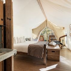 a bed sitting inside of a white tent next to a sink and counter in a room