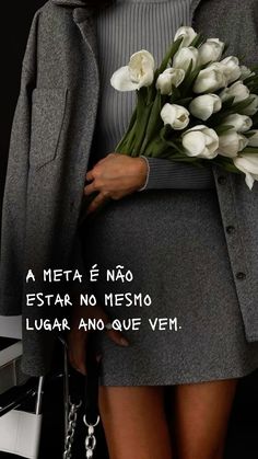 a woman holding flowers in her hand with the caption'a meta e nao estar no mesmo, lugar and que vem