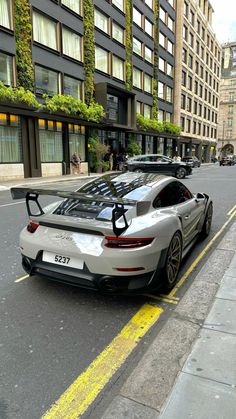 a silver sports car parked on the side of the road in front of a tall building