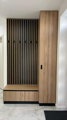 a wooden bench sitting in the middle of a room next to a wall with vertical slats on it