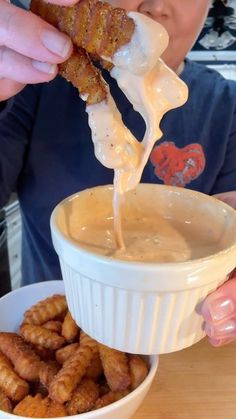 a person dipping some food into a bowl