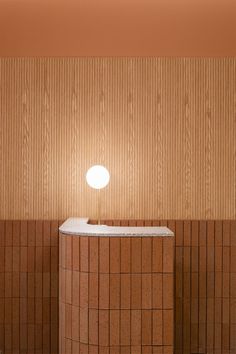 a lamp sitting on top of a counter next to a wooden wall with tiles around it