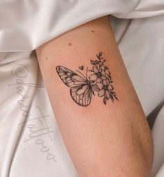 a small butterfly with flowers on its back side arm tattooing it's wings