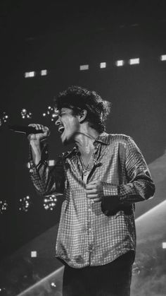 a black and white photo of a man singing into a microphone