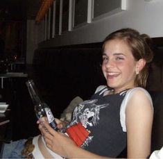 a woman sitting on a couch holding a cell phone in her hand and smiling at the camera