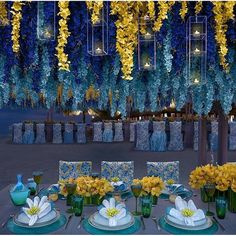 the table is set with yellow flowers and blue vases, plates and napkins